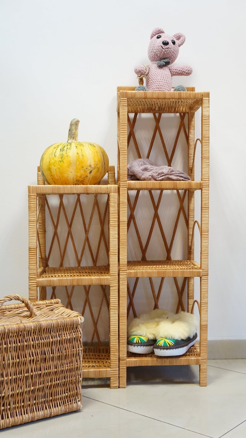 May include: Two wicker shelves with a pumpkin on top of one and a stuffed animal on top of the other. The shelves are made of woven wicker and have a diamond pattern. The shelves are standing on a tiled floor.