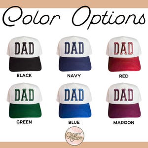 Puede incluir: Seis opciones de color diferentes para una gorra de b&eacute;isbol blanca con la palabra "DAD" bordada en negro, azul marino, rojo, verde, azul y granate.