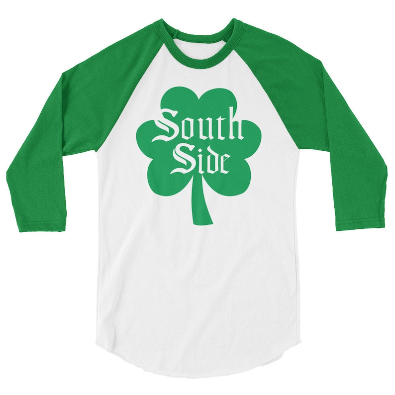 May include: A white and green baseball t-shirt with a shamrock design and the text "South Side" in a white font.