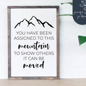 May include: A white wooden sign with a black mountain silhouette and the text "YOU HAVE BEEN ASSIGNED TO THIS mountain TO SHOW OTHERS IT CAN BE moved".