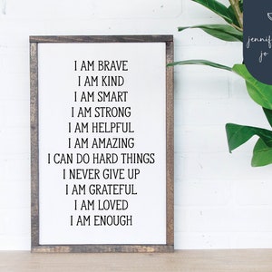 May include: A framed wooden sign with white background and black text. The text reads: "I am brave, I am kind, I am smart, I am strong, I am helpful, I am amazing, I can do hard things, I never give up, I am grateful, I am loved, I am enough."