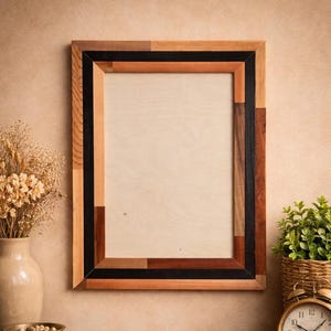 May include: A rectangular wooden picture frame with a multi-toned design. The frame features a natural wood grain, with accents of black, brown, and lighter wood tones. The frame is empty, ready for a photo or artwork. The frame is approximately 16 x 20 inches.