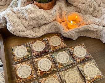 May include: Twelve small clear plastic bags filled with dried herbs and fruit peels. Each bag has a brown paper circle label with the text "Timeless Blends" and the name of a tea blend. The blends include "Autumn Spice", "Apple Tart", "Orange Chai", "Sweet Lemon", "Cranberry Ginger", "Lemon Lavender", "Herbal Citrus", "Autumn Spice", "Orange Hibiscus", "Forest Floor", "Lemon & Ginger", and "Earl Grey & Orange".