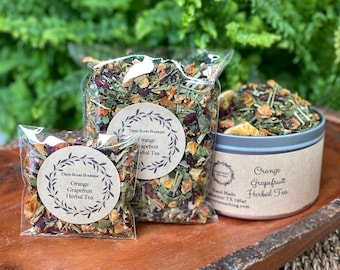 May include: Three bags of loose leaf herbal tea blend with orange and grapefruit flavors. The bags are labeled "Three Roots Boutique Orange Grapefruit Herbal Tea".