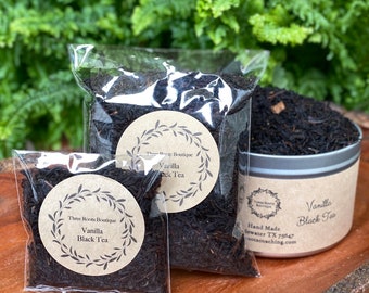 Puede incluir: Dos bolsas de té negro de hoja suelta con sabor a vainilla. Las bolsas están etiquetadas con "Three Roots Boutique Vanilla Black Tea".