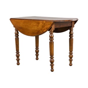 May include: A wooden drop-leaf table with a warm brown finish. The table has a semi-circular shape when the leaf is down and stands on four turned legs. The table is a classic piece of furniture.