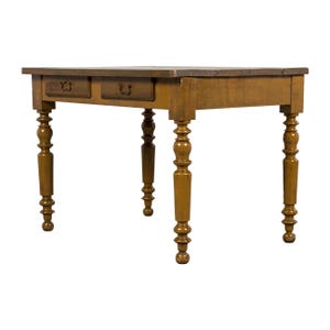 May include: A wooden desk with two drawers and turned legs. The desk is a warm brown color with a darker brown top. The legs are intricately carved, adding a touch of elegance to the piece. The desk is approximately 48 inches wide.