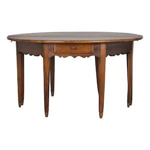 May include: A round, antique wooden table with a single drawer and scalloped apron. The table has four slender, tapered legs and is finished in a warm, medium-brown tone. The drawer features a small, round wooden knob.