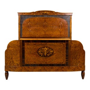 May include: An antique wooden bed frame with a headboard and footboard. The bed frame is made of a dark wood with a patterned grain. The headboard features a decorative floral inlay. The bed frame has curved edges and turned legs.
