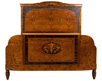 May include: An antique wooden bed frame with a headboard and footboard. The bed frame is made of a dark wood with a patterned grain. The headboard features a decorative floral inlay. The bed frame has curved edges and turned legs.