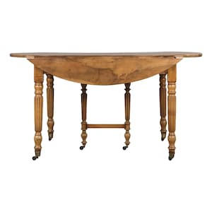 Puede incluir: Mesa antigua de alas abatibles de color marrón claro, con tapa redondeada. Las patas torneadas presentan detalles tallados y pequeñas ruedas de latón. La mesa es de madera y de estilo clásico. Mide unos 152 cm de largo.
