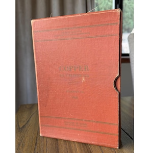 以下が含まれることがあります： Copper in California, Bulletin 144, 1948と記されたDivision of Mines発行の長方形のオレンジがかった赤色のハードカバー本。表紙には濃い緑色の水平線と文字が印刷されており、右側には指をかけるための切り欠きがある。