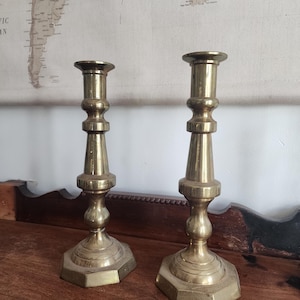 May include: A pair of antique brass candle holders with a fluted design and octagonal bases.