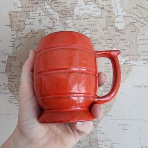 Op de afbeelding: Een feloranje keramische mok met een handvat. De mok heeft een getextureerd, geribbeld ontwerp.