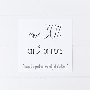 May include: A white sign with black text that reads "save 30% on 3 or more *discount applied automatically at checkout*"