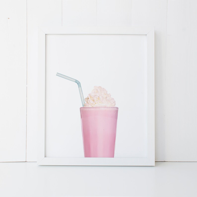 May include: A pink milkshake with whipped cream and a blue straw in a clear glass. The milkshake is in a white frame.