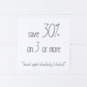 May include: A white sign with black text that reads "save 30% on 3 or more *discount applied automatically at checkout*"