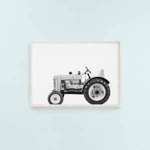 May include: A black and white photograph of a vintage tractor with a visible engine. The tractor is on a white background.