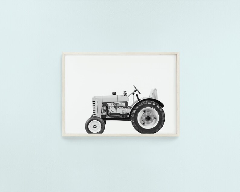May include: A black and white photograph of a vintage tractor with a visible engine. The tractor is on a white background.