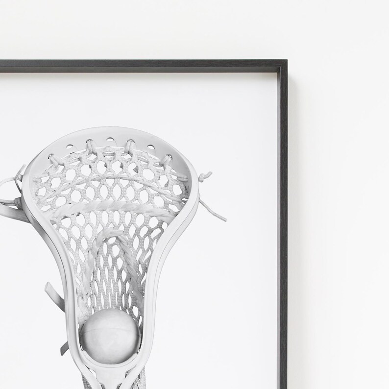 K&ouml;nnte beinhalten: Ein wei&szlig;er Lacrosse-Schl&auml;ger mit einem wei&szlig;en Ball im Netz. Der Schl&auml;ger befindet sich in einem schwarzen Rahmen.
