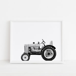 May include: A black and white photograph of a vintage toy tractor in a white frame.