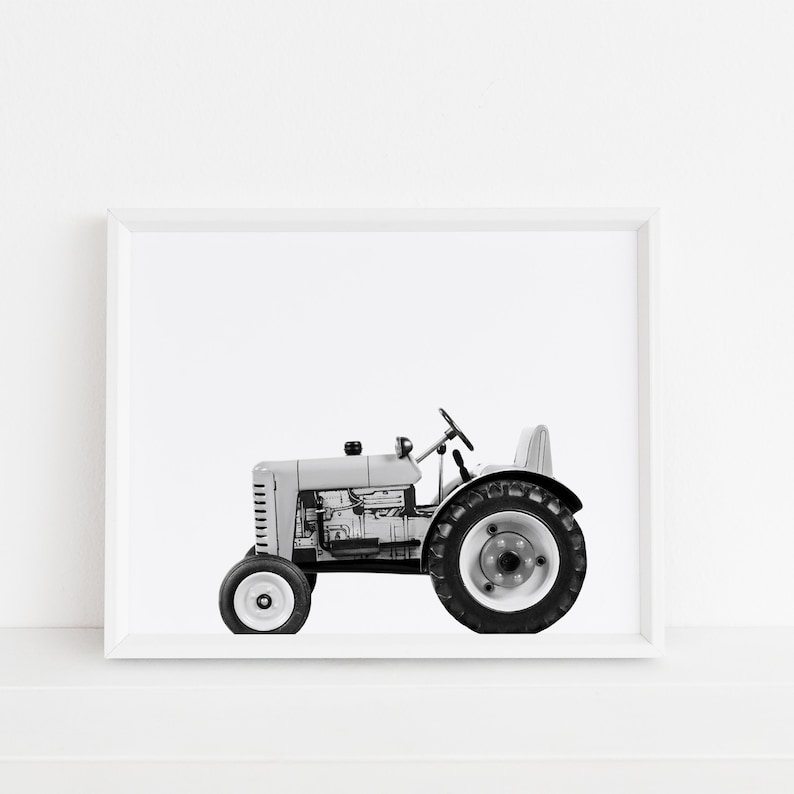 May include: A black and white photograph of a vintage toy tractor in a white frame.