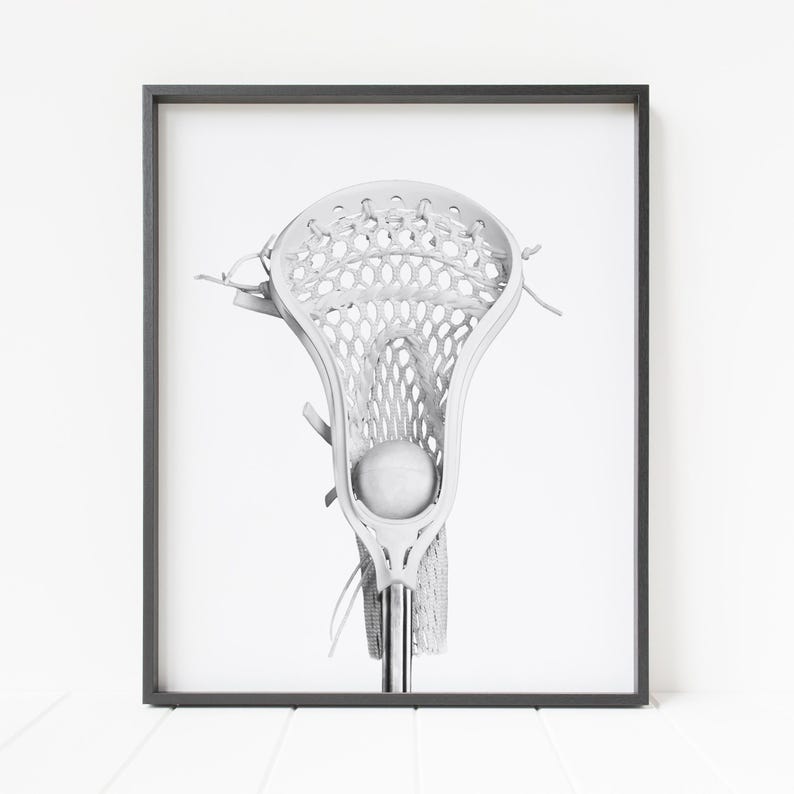 K&ouml;nnte beinhalten: Ein wei&szlig;er Lacrosse-Schl&auml;ger mit einem wei&szlig;en Ball im Netz. Der Schl&auml;ger befindet sich vor einem wei&szlig;en Hintergrund.