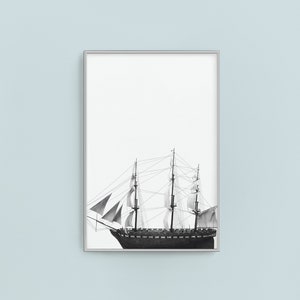 May include: A black and white illustration of a sailing ship with billowing sails against a white background. The ship is framed in a silver frame.
