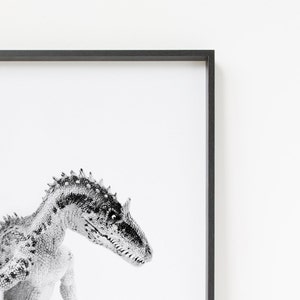 May include: Black and white photograph of a dinosaur head and neck. The dinosaur is looking to the right of the frame. The background is white.