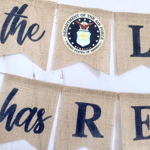 May include: A burlap banner with the words "the has re" and the seal of the Department of the Air Force, United States of America.