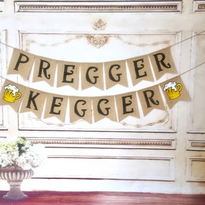 May include: A burlap banner with the text "Pregger Kegger" in black letters. The banner has two yellow beer mugs with white foam on top.