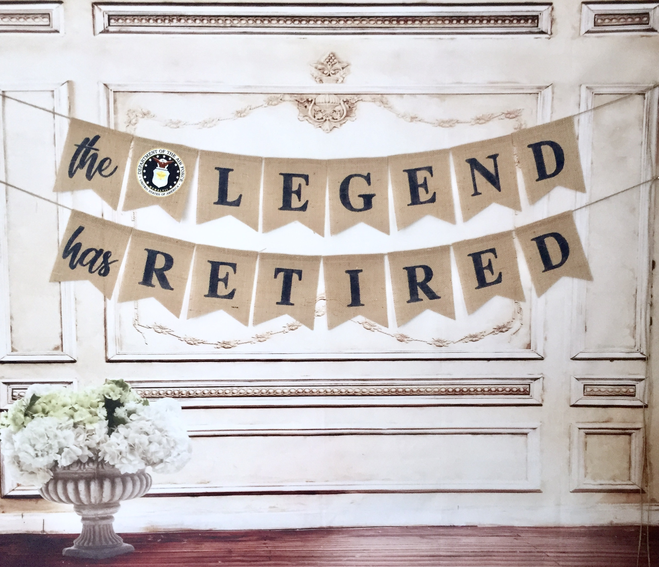 May include: A burlap banner with the text "the LEGEND has RETIRED" in black lettering. The banner has a small blue and white emblem of the United States Air Force.