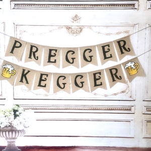 May include: A burlap banner with the text "Pregger Kegger" in black letters. The banner has two yellow beer mugs with white foam on top.