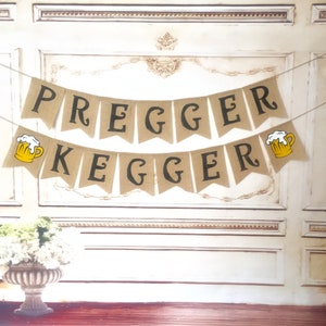 May include: A burlap banner with the text "Pregger Kegger" in black letters. The banner is decorated with two yellow beer mugs with white foam.