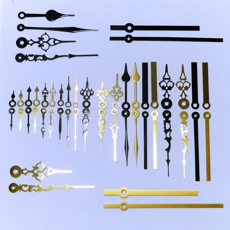 May include: Assortment of clock hands in various styles and colours, including black, gold, and silver. The hands are made of metal and have different lengths and designs. Some hands have a simple design, while others have intricate details.