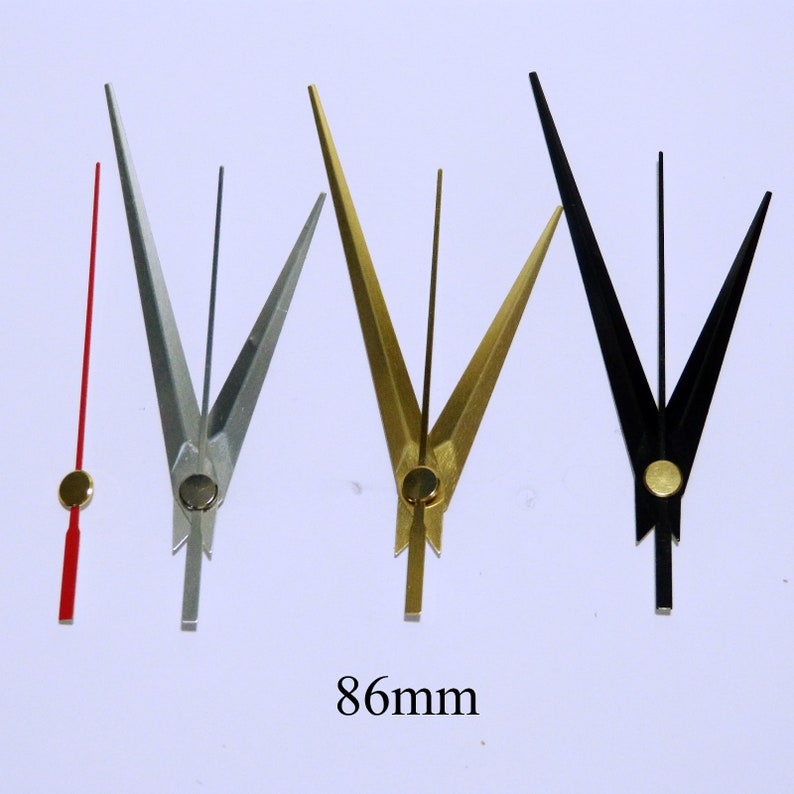 May include: Four clock hands in different colors: red, silver, gold, and black. The hands are 86 mm long and have a pointed tip.