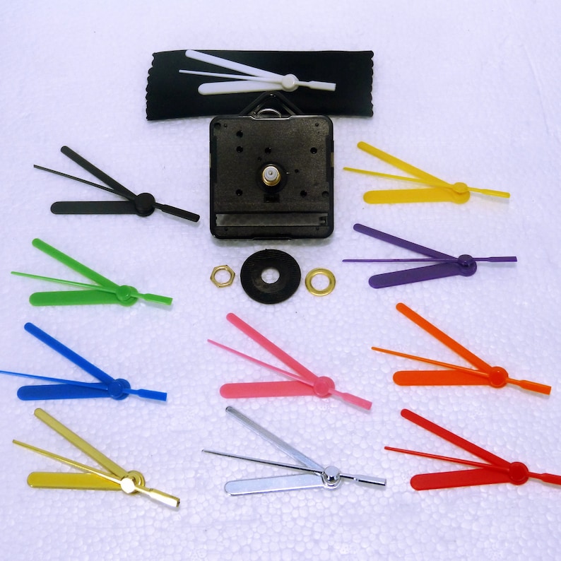 K&ouml;nnte beinhalten: Uhrwerkmechanismus mit einem schwarzen Kunststoffgeh&auml;use und einem Satz Uhrzeiger in verschiedenen Farben, darunter Wei&szlig;, Schwarz, Gr&uuml;n, Blau, Rosa, Silber, Rot, Orange und Gelb.