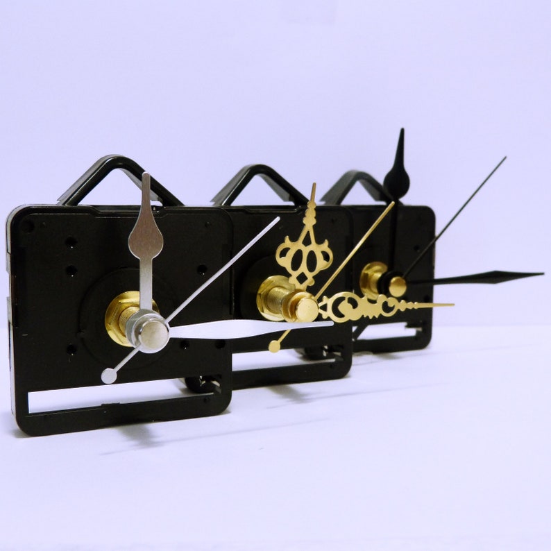 May include: Three clock mechanisms with black plastic housings and different styles of clock hands. The hands are silver, gold, and black.