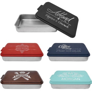 May include: Set of four personalized cake pans with lids. The lids are red, blue, brown, and turquoise. The lids are engraved with different designs and text. The text on the lids includes "Homemade by Kathy Bozden", "The Coffee Shop", "Baked by Lori Haggle", and "Morgan".