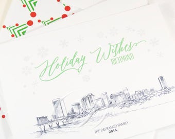 May include: White holiday greeting cards with a green and white design. The cards feature the text "Holiday Wishes Richmond" with a sketch of a city skyline. The envelopes have a pattern of green trees and red dots.