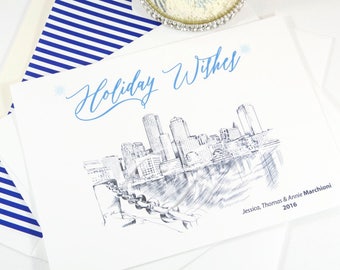 May include: White holiday greeting card with a blue skyline illustration and the words "Holiday Wishes" in cursive. The card includes the names "Jessica, Thomas & Annie Marchioni 2016". A blue and white striped envelope is visible.