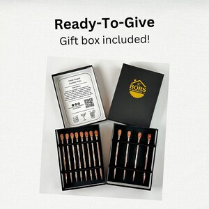 May include: Two black boxes containing hand forged cocktail picks. One box has a label that says "Hand Forged Cocktail Picks" and includes care instructions. The other box has a label that says "BORS DESIGN CO.".