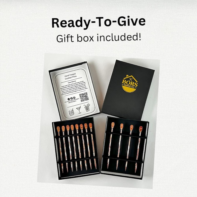 May include: Two black boxes containing hand forged cocktail picks. One box has a label that says "Hand Forged Cocktail Picks" and includes care instructions. The other box has a label that says "BORS DESIGN CO.".