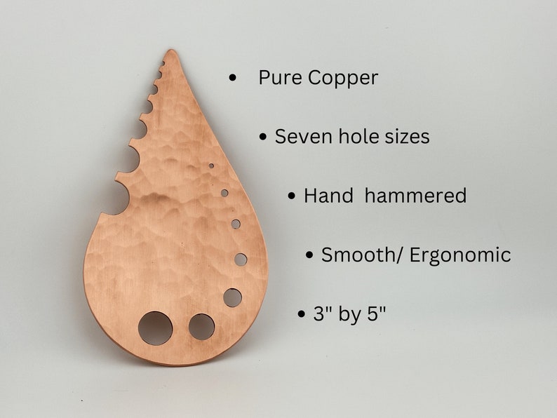 May include: A teardrop-shaped copper tool with seven different sized holes and a serrated edge. The tool is hand-hammered and measures 3 inches by 5 inches.