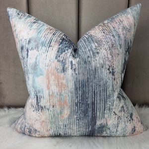 May include: A decorative throw pillow with a blue, pink, and white abstract pattern. The pillow has a soft, textured fabric.