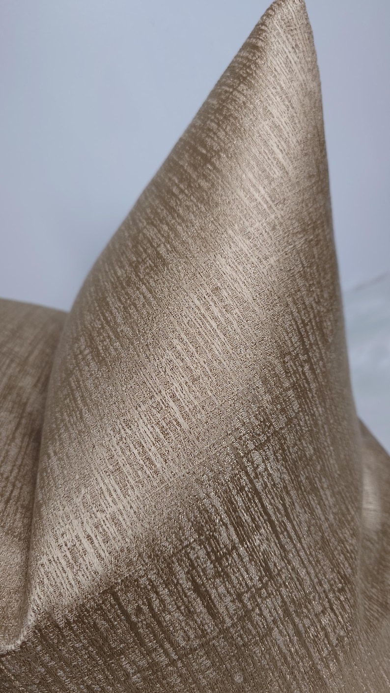May include: A close-up of a gold-coloured fabric with a textured, woven pattern. The fabric has a subtle sheen and a slightly raised surface.