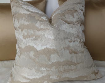 May include: A decorative throw pillow with a beige and white abstract pattern. The pillow is made of a soft, textured fabric.