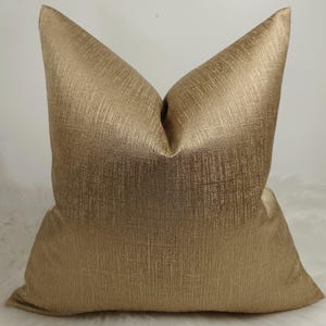 May include: A gold pillow cover with a subtle textured pattern. The pillow cover is made of a soft, luxurious fabric.