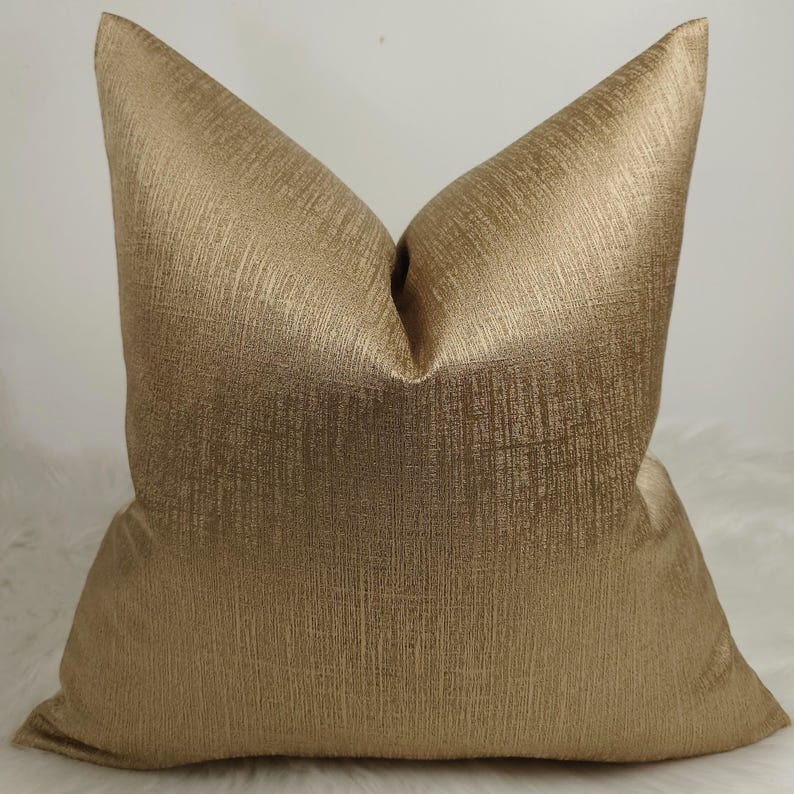 May include: A gold pillow cover with a subtle textured pattern. The pillow cover is made of a soft, luxurious fabric.