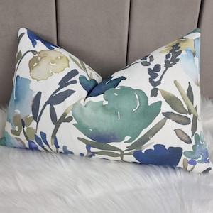 May include: A white pillow with a blue, green, and yellow floral pattern. The pillow is made of a soft, comfortable fabric and has a subtle watercolor effect.
